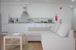 a white living room with a white couch and a table at Lugar dos Louros 2 in Estreito da Calheta