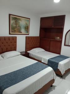 Habitación con 2 camas y una foto en la pared. en Hotel Exito Barranquilla, en Barranquilla