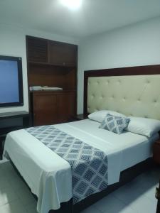 a bedroom with a large bed and a television at Hotel Exito Barranquilla in Barranquilla