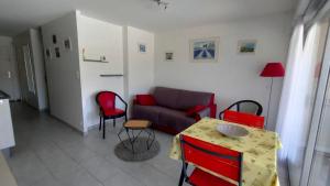 ein Wohnzimmer mit einem Sofa, einem Tisch und Stühlen in der Unterkunft Entre terre mer et golf in Mandelieu-la-Napoule