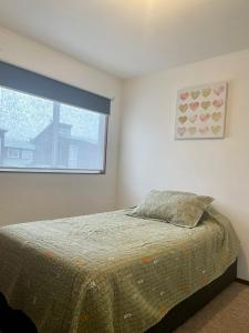 1 dormitorio con cama y ventana en Cómoda y amplía casa con Quincho, en Punta Arenas