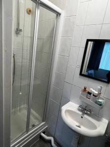 a white bathroom with a sink and a shower at Luton Airport £40 per night, best value in Luton