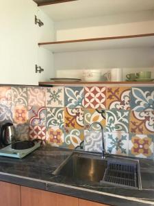 cocina con fregadero y pared de azulejos en Bharata Beach House, en Keramas