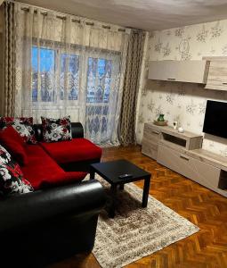 - un salon avec un canapé rouge et une table dans l'établissement Hellen's Ultracentral Apartament, à Buzău