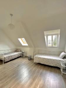 a attic room with two beds and a window at Maison spacieuse de Lila avec 3 places de parkings in Crèvecoeur-le-Grand