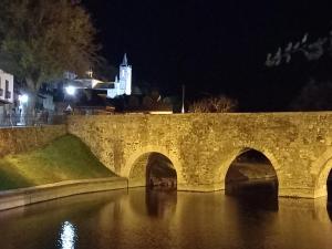 uma ponte de pedra sobre um rio à noite em Hotel Rural Virgen del Carmen em Molinaseca