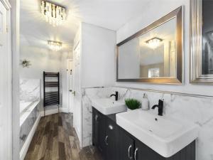 a bathroom with two sinks and a mirror and a tub at Montague House in Ross on Wye