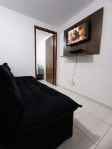 a bedroom with a black bed and a tv on the wall at Apartamento Aconchegante in Brasilia