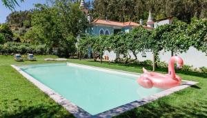 une piscine avec un flamant gonflable rose en face d'une maison dans l'établissement Torres da Vila, à Anadia