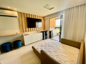 a bedroom with a bed and a flat screen tv at Flat luxo torre 07 Eco Resort Praia dos Carneiros in Tamandaré +53 photos