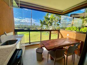 een keuken met een tafel en stoelen en een groot raam bij Flat luxo torre 07 Eco Resort Praia dos Carneiros in Tamandaré