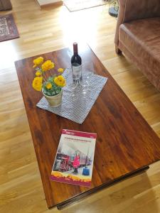 uma mesa com um livro e uma garrafa de vinho e flores em Ferienwohnung an der Salamanderburg em Schierke