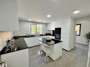 a kitchen with white cabinets and a black counter top at Villa Paraiso in Jávea