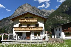 a house with a balcony in front of a mountain at Ferienhaus Haueis in Tumpen