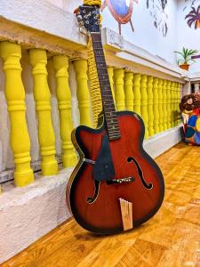 a guitar sitting on the floor next to a wall at Awaara Backpackers Hostel, Alibag in Alibag