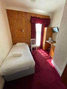 a hotel room with a bed and a chair and a window at Fjaerland Hotel in Great Yarmouth
