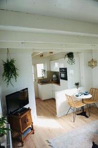 a living room with a tv and a table and a kitchen at Tiny House Noordwijk aan Zee in Noordwijk