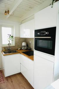 cocina con armarios blancos y fogones negros en Tiny House Noordwijk aan Zee en Noordwijk