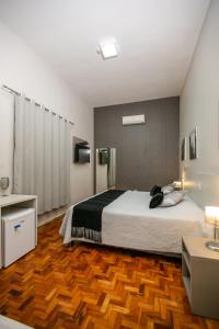 a bedroom with a large bed and a wooden floor at Botucatu Hotel in Botucatu