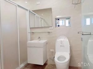 a white bathroom with a toilet and a sink at Lily Garden Homestay in Yilan City