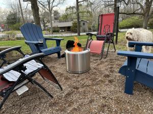 een vuurplaats in een tuin met stoelen en een hond bij Luxury Smart Bungalow in Fayetteville