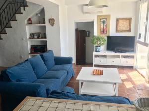 sala de estar con sofá azul y TV en The Townhouse, Iznajar, en Iznájar