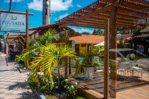 uma pérgola de madeira com plantas em frente a um restaurante em Pousada Sete Mares na Barra de São Miguel