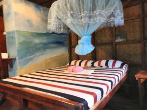 a bedroom with a bed with a curtain and a painting at Nuts Huts in Loboc
