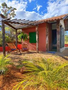 a house with two chairs and a greenboard at Aldeia da Serra Lapinha in Santana do Riacho