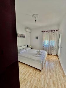 a bedroom with a white bed and a wooden floor at Albania Dream Apartment 31 in Metogjashta