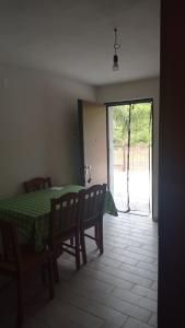 comedor con mesa verde y sillas y puerta corredera de cristal en casa vacanza Green House Casalvelino, en Omignano Scale