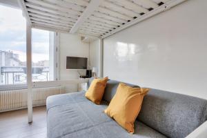 ein Wohnzimmer mit einem grauen Sofa und gelben Kissen in der Unterkunft Studio - Appartement Quartier Tour Eiffel 3 in Paris