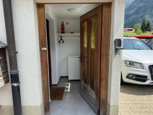 una puerta a una casa con un coche aparcado al lado en Alpina Appartment Kandersteg en Kandersteg