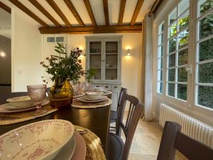 ein Esszimmer mit einem Tisch, Stühlen und Fenstern in der Unterkunft Villa normande - Les Crapauds Fous in Deauville
