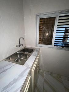 eine Küche mit einem Waschbecken und einem Fenster in der Unterkunft Résidence Le TOUNKARANKE ACI 2000 in Bamako
