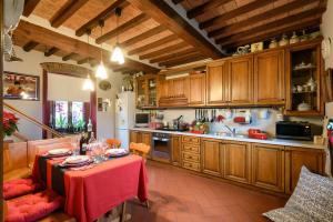 una cocina con armarios de madera y una mesa con un mantel rojo. en Villa "Corte de' Baldi", en Ortignano Raggiolo