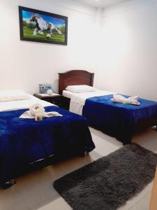 una camera con due letti con lenzuola blu e un dipinto sul muro di DESCANSO EN SUTATENZA BOYACA a Sutatenza