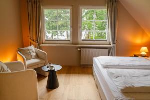 a bedroom with a bed and a chair and a window at Seehotel Köllnitz in Wochowsee