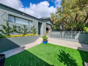 a backyard with a white fence and grass at Virginia Avenue Villas - Adriatica and Botanica in Cape Town