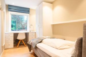 1 dormitorio con cama, ventana y escritorio en Cozy House en Oslo