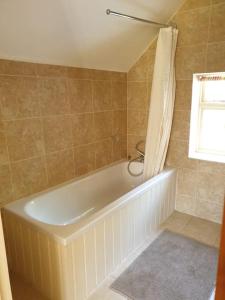 a white bath tub in a bathroom with a window at Beautiful thatched cottages in Brentwood. in Kelvedon Hatch