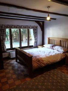 um quarto com uma cama grande num quarto com janelas em Beautiful thatched cottages in Brentwood. em Kelvedon Hatch