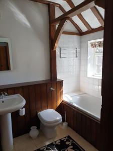 uma casa de banho com um WC, uma banheira e um lavatório. em Beautiful thatched cottages in Brentwood. em Kelvedon Hatch