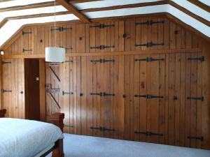 a bedroom with wood paneled walls and a bed at Beautiful thatched cottages in Brentwood. in Kelvedon Hatch