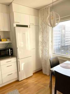 PASILA Modern flat centrally located في هلسنكي: مطبخ مع ثلاجة وطاولة ونافذة