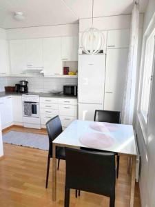 a white kitchen with a table and chairs in it at PASILA Modern flat centrally located in Helsinki