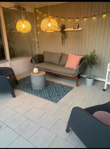 a patio with a couch and a table and lights at Huset ved søen tæt på Herning og MCH og boxen 90 m2 in Sunds