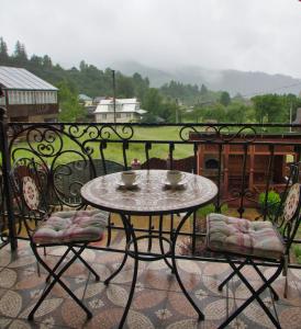 een tafel op een balkon met 2 kopjes en stoelen bij Emerald House in Mykulychyn