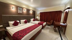 a hotel room with two beds and a desk at Hotel Annamalai International in Puducherry