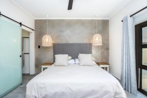 a bedroom with a large white bed and two tables at Seaview Cottage Barry @ Surf Spray in Southbroom